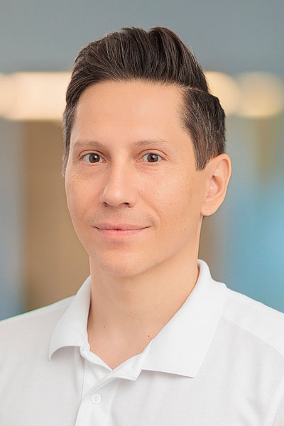 Victor Stefan trägt ein weißes Hemd und steht vor einem unscharfen Hintergrund